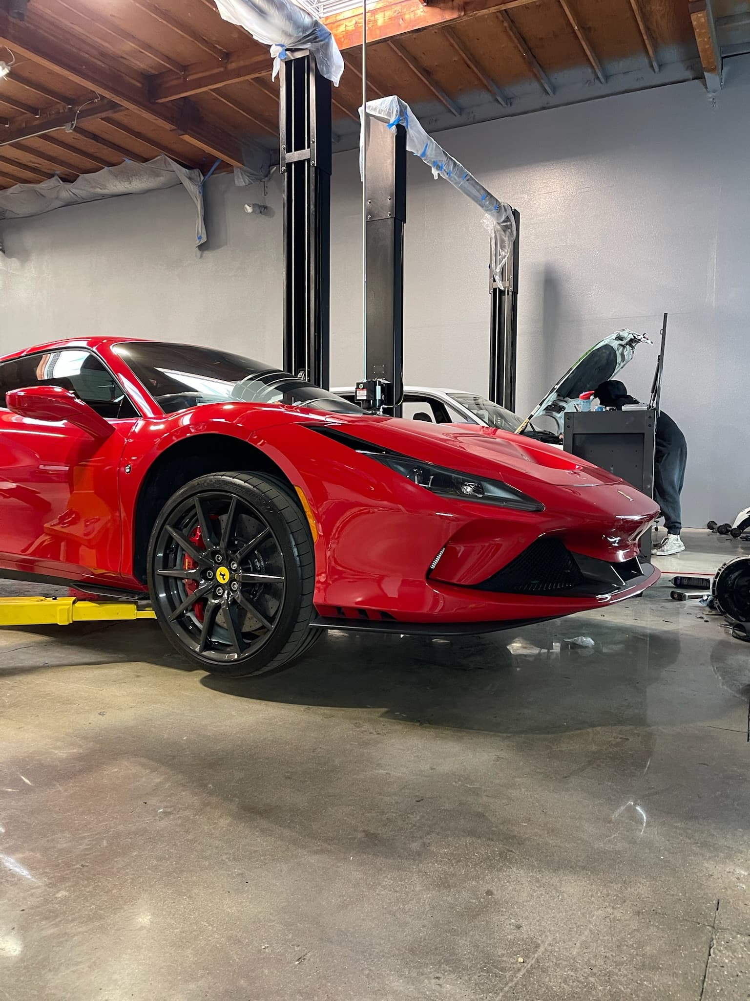 Red Ferrari F8 Tributo on a lift inside the 961 Motorsport workshop
